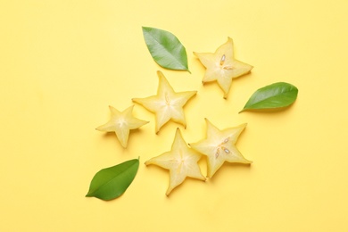 Delicious carambola slices on yellow background, flat lay