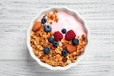 Photo of Tasty homemade granola served on white wooden table, top view. Healthy breakfast