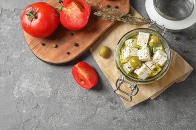 Flat lay composition with pickled feta cheese in jar on grey table