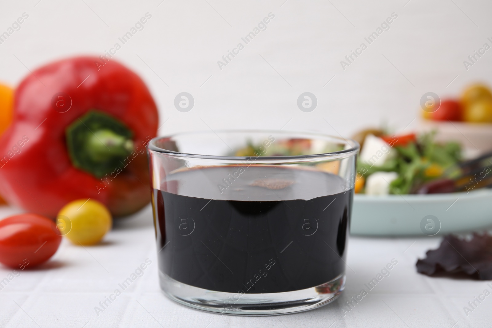 Photo of Vinegar in glass on white tiled table, closeup