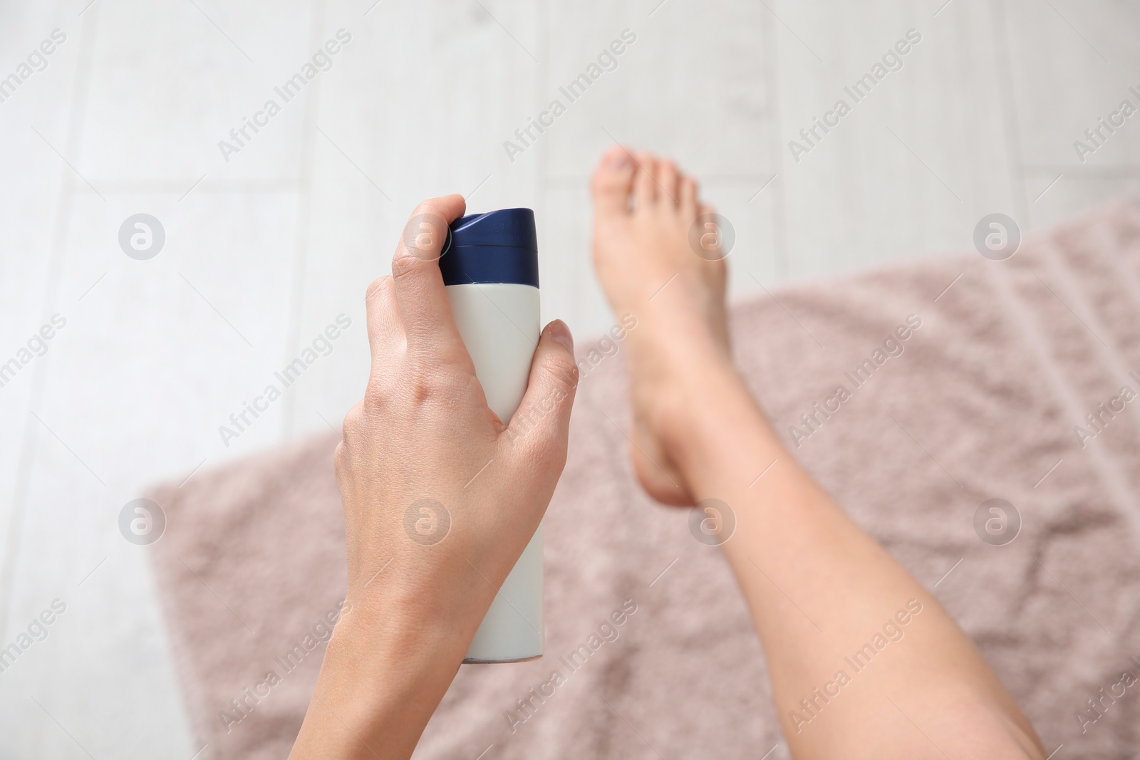 Photo of Young woman using deodorant for feet at home, closeup