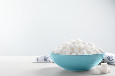 Photo of White sugar cubes on wooden table, space for text