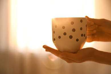 Photo of Woman holding cup of drink on blurred background, closeup. Lazy morning