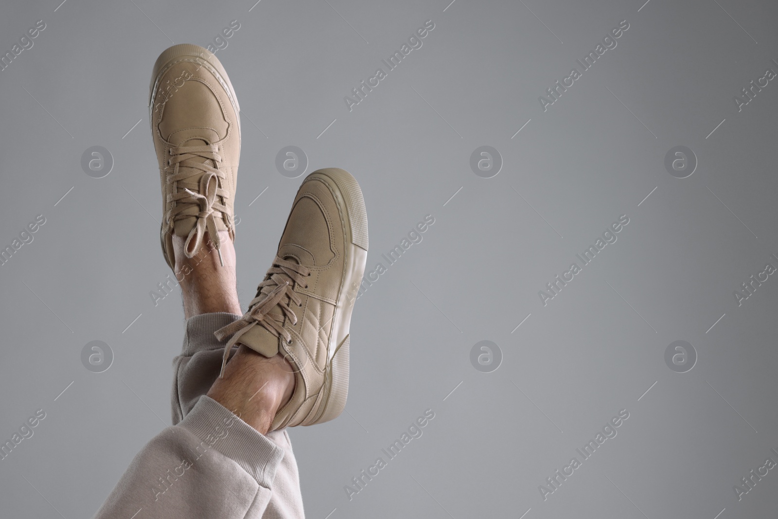 Photo of Man wearing stylish sneakers on light grey background, closeup. Space for text