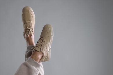 Man wearing stylish sneakers on light grey background, closeup. Space for text