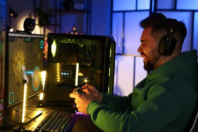 Photo of Man playing video games with controller at table indoors