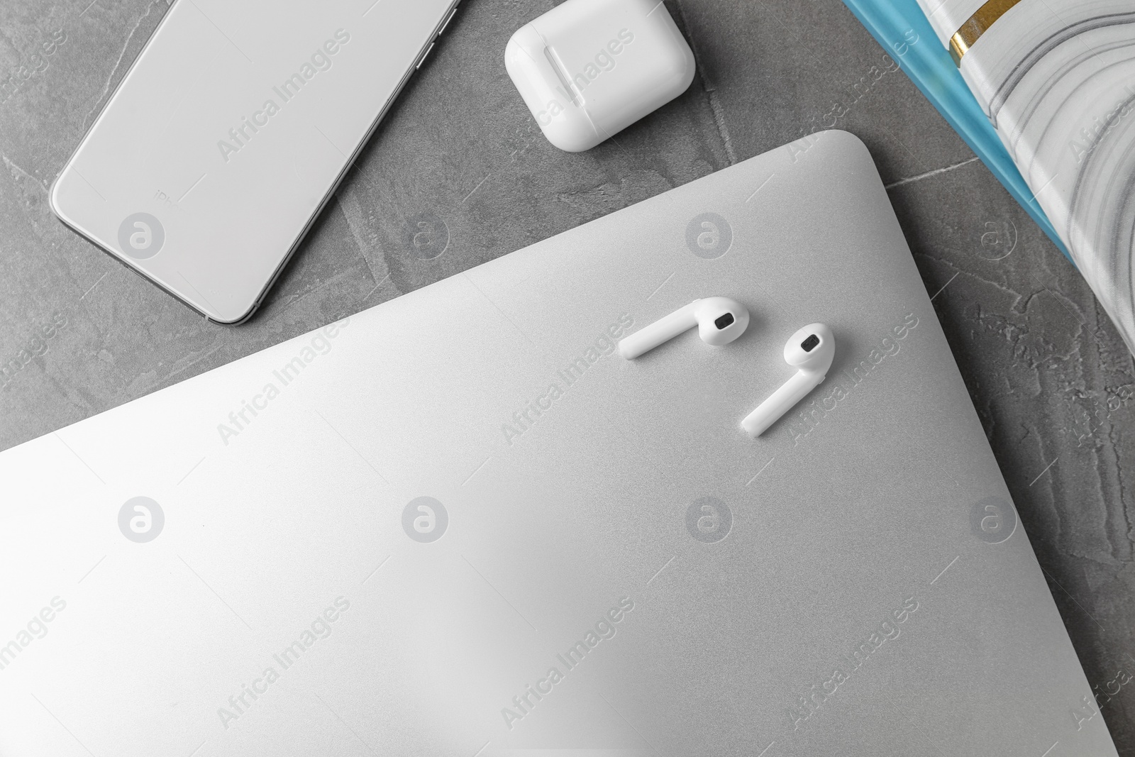 Photo of Flat lay composition with wireless earphones and laptop on grey stone table