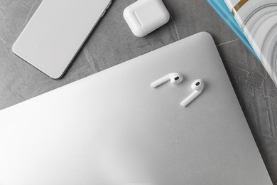 Photo of Flat lay composition with wireless earphones and laptop on grey stone table