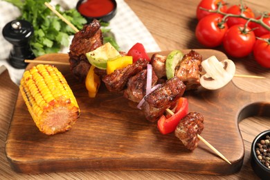 Photo of Delicious shish kebabs with vegetables on wooden table