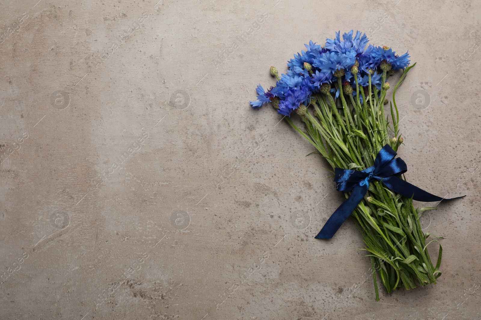 Photo of Bouquet of beautiful cornflowers on grey table, top view. Space for text