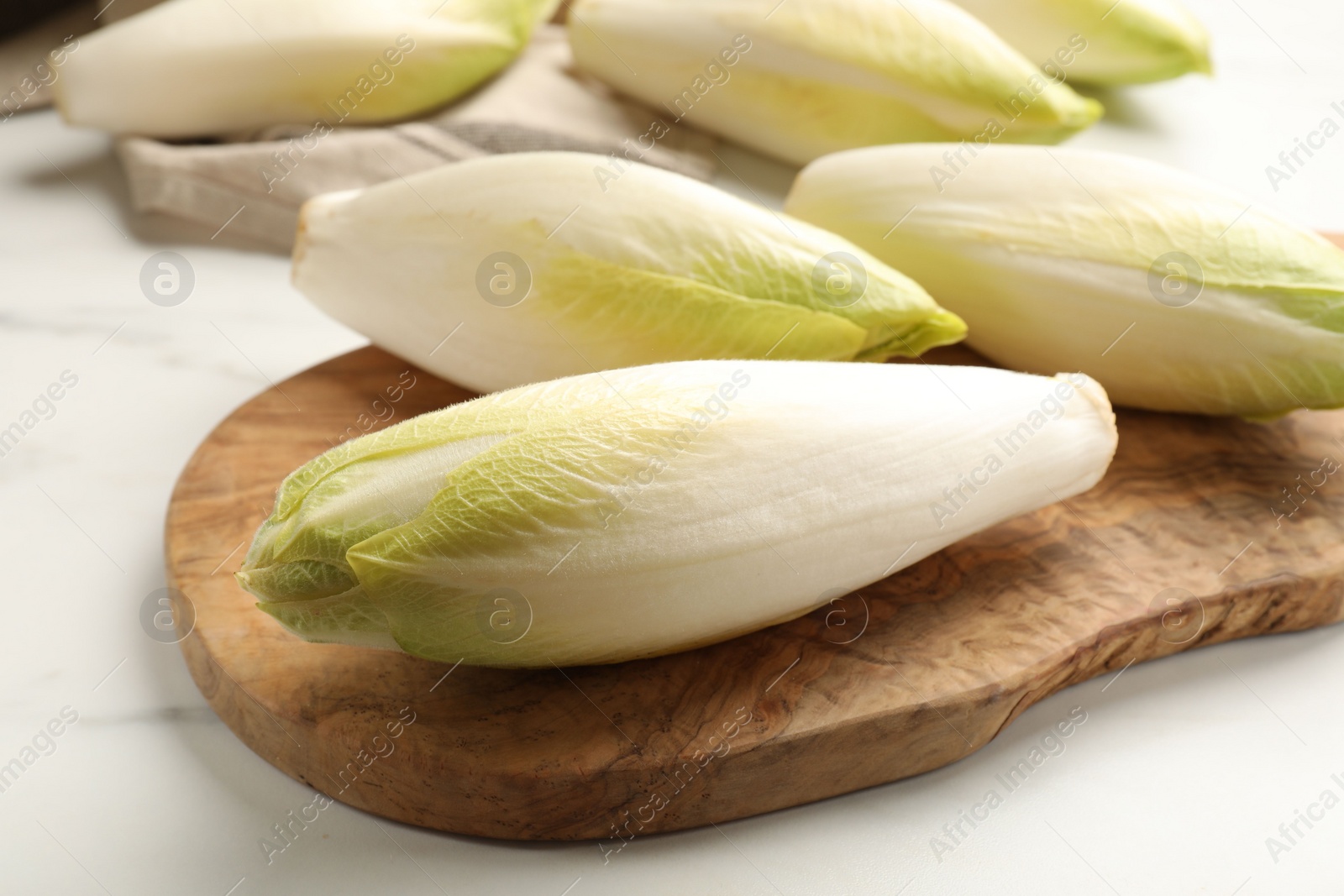 Photo of Raw ripe chicories on white marble table, closeup