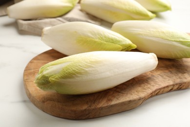 Photo of Raw ripe chicories on white marble table, closeup