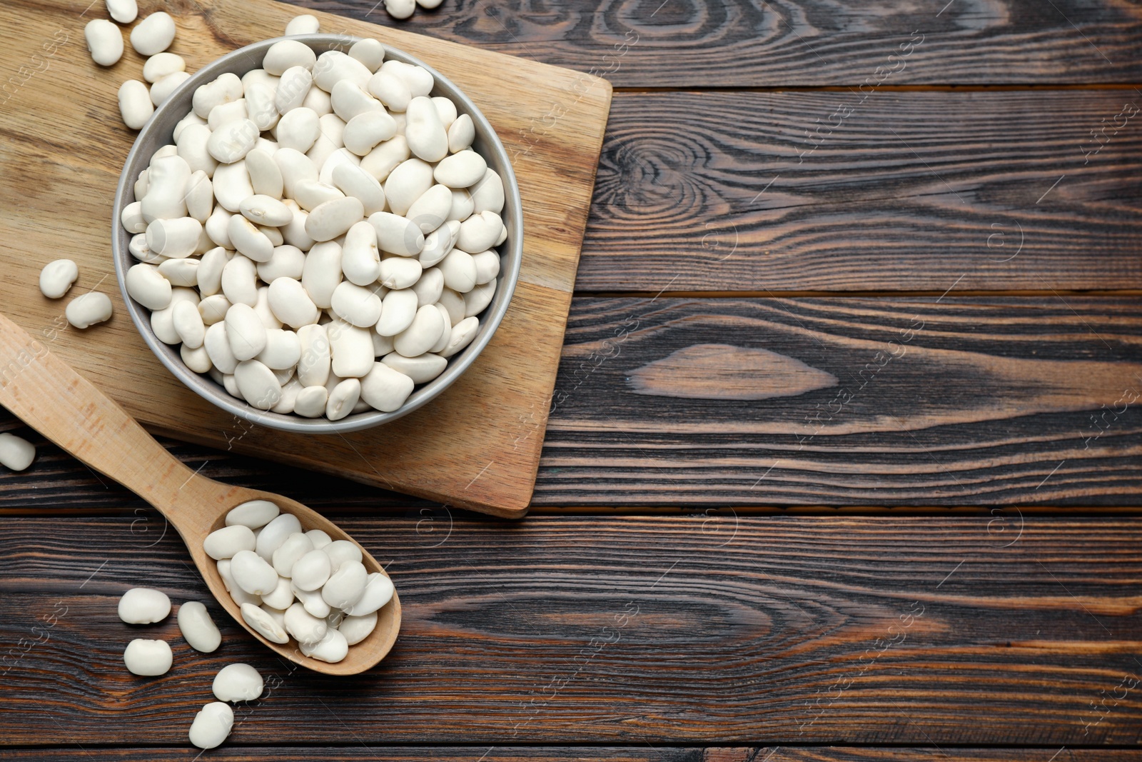 Photo of Raw white beans on wooden table, flat lay. Space for text