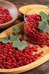 Photo of Ripe red currants and leaves on wooden table, closeup