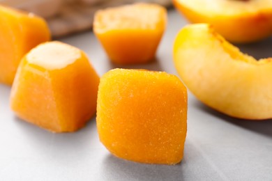 Frozen nectarine puree cubes and ingredient on light grey table, closeup