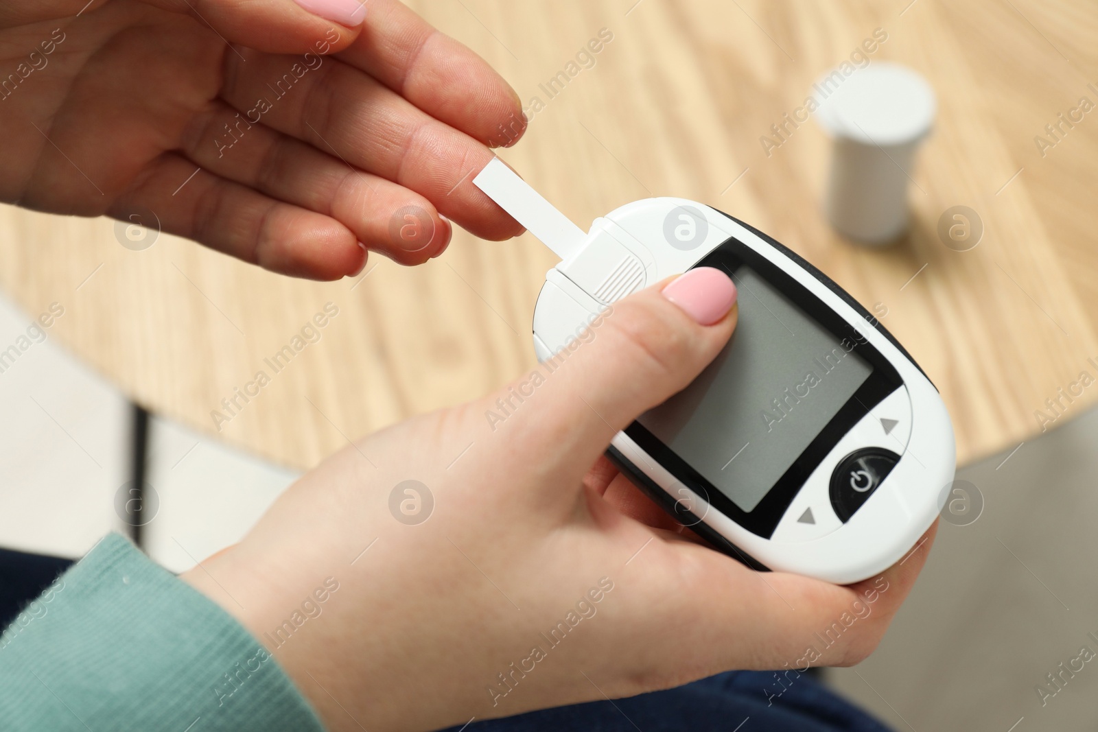 Photo of Diabetes. Woman checking blood sugar level with glucometer at home, top view