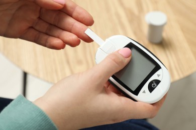 Diabetes. Woman checking blood sugar level with glucometer at home, top view