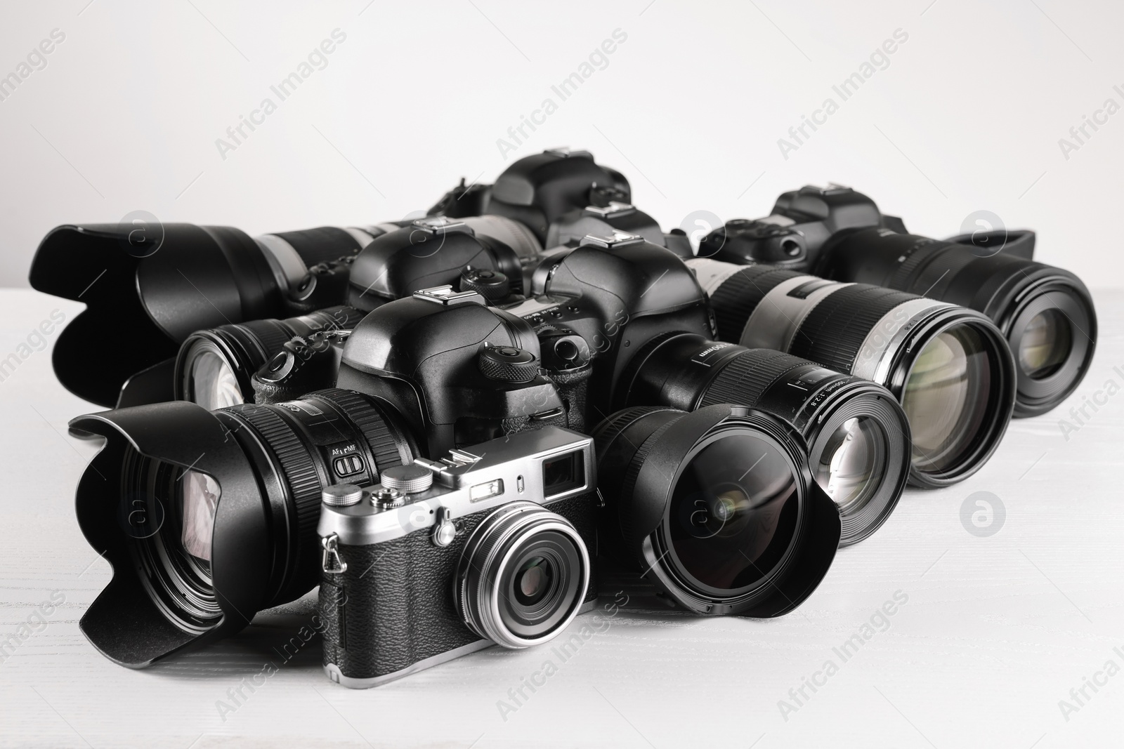 Photo of Modern cameras on white wooden table, closeup