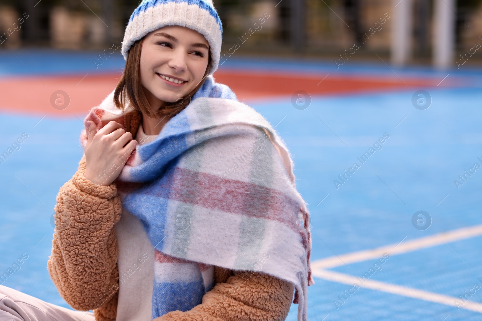 Photo of Beautiful woman in warm scarf and hat outdoors, space for text