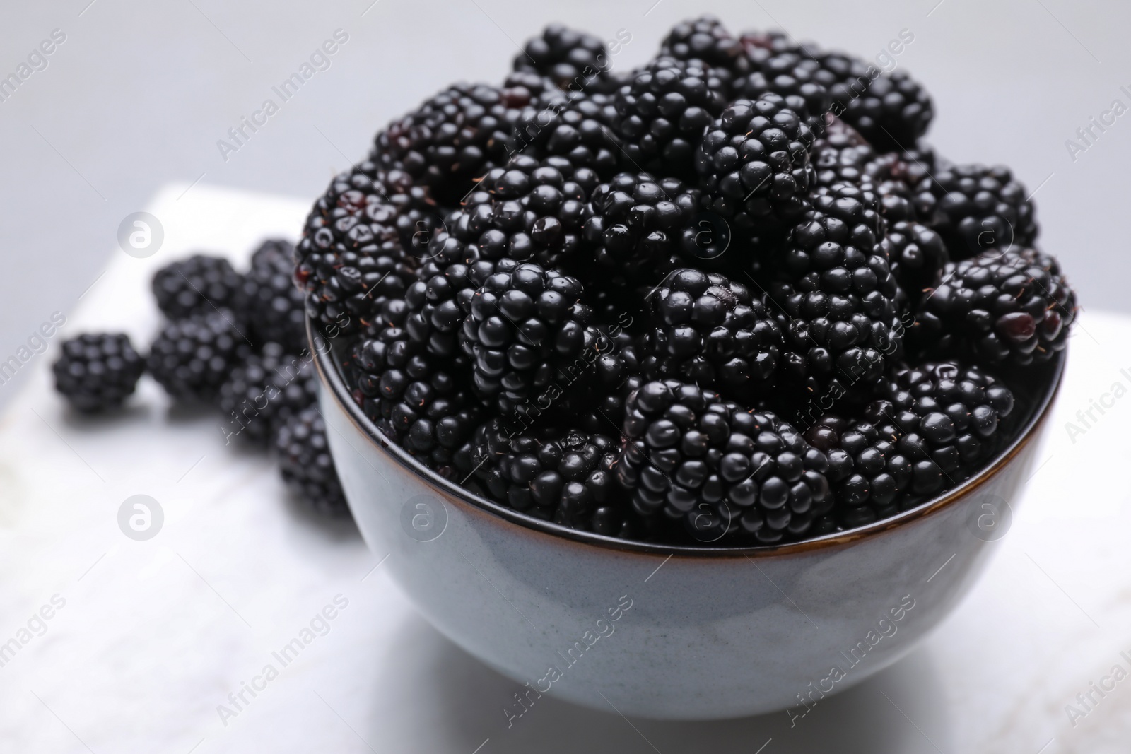 Photo of Fresh ripe blackberries in bowl on table, closeup