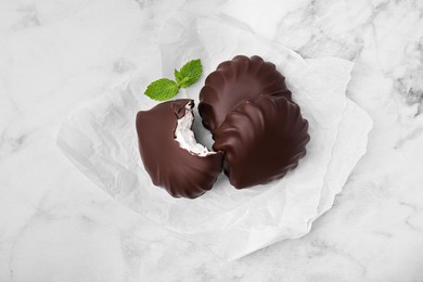 Photo of Delicious chocolate covered marshmallows with mint on white marble table, flat lay