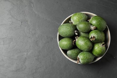 Fresh green feijoa fruits in bowl on black table, top view. Space for text