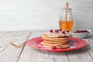 Plate with delicious pancakes on wooden table