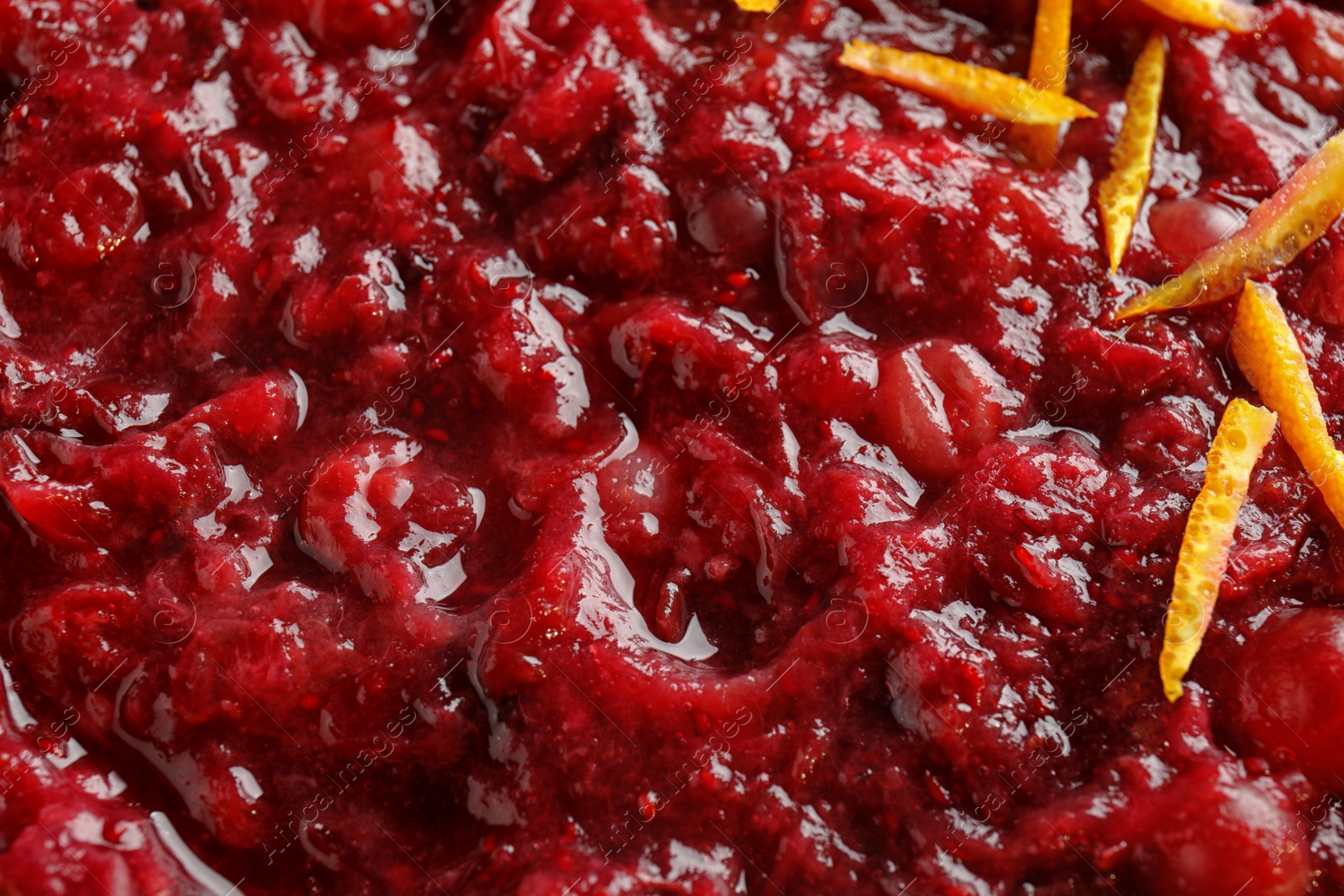 Photo of Tasty cranberry sauce with citrus zest as background, top view