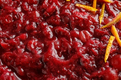 Photo of Tasty cranberry sauce with citrus zest as background, top view