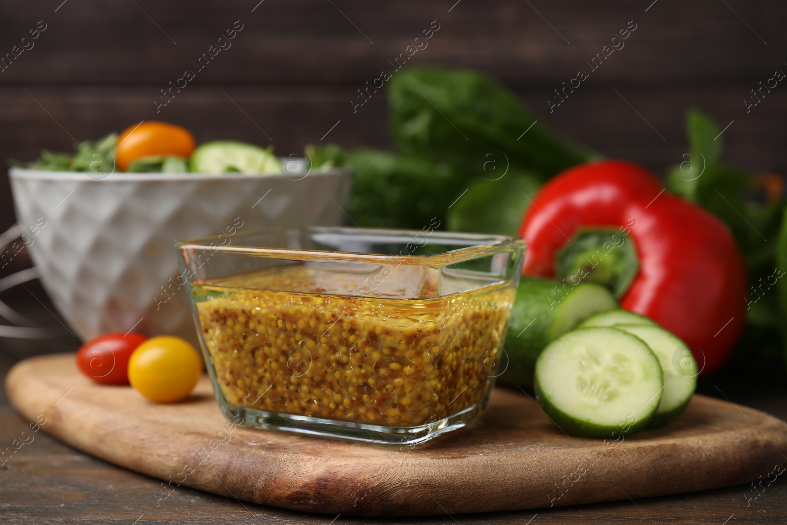 Photo of Tasty vinegar based sauce (Vinaigrette) in bowl and products on wooden table, closeup