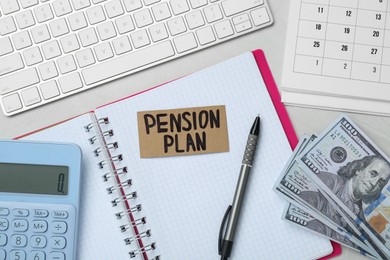 Photo of Card with words Pension Plan, banknotes, calculator and notebook on white office table, flat lay