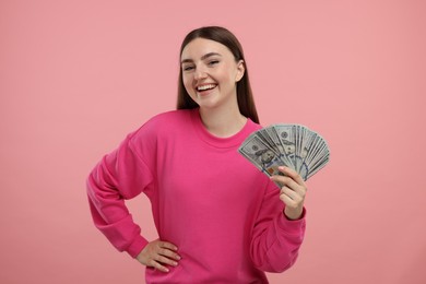 Happy woman with dollar banknotes on pink background