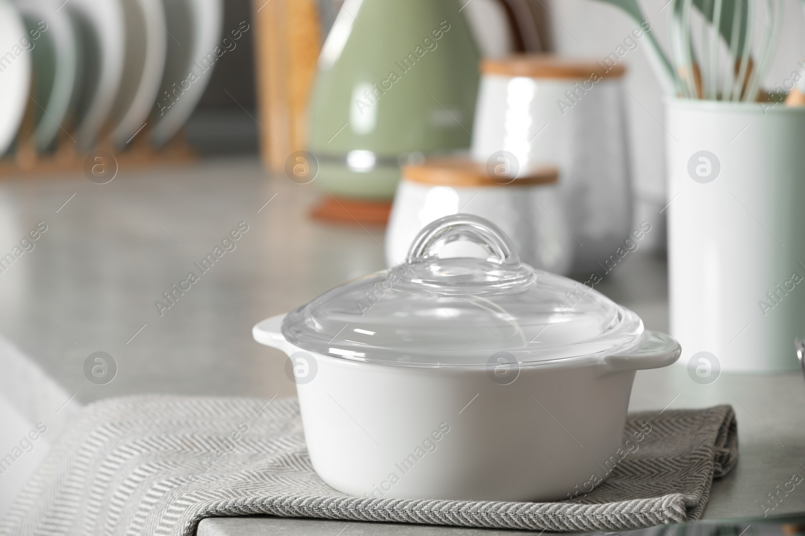 Photo of Ceramic pot with glass lid on light grey countertop in kitchen