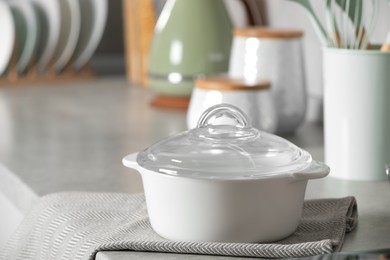 Photo of Ceramic pot with glass lid on light grey countertop in kitchen