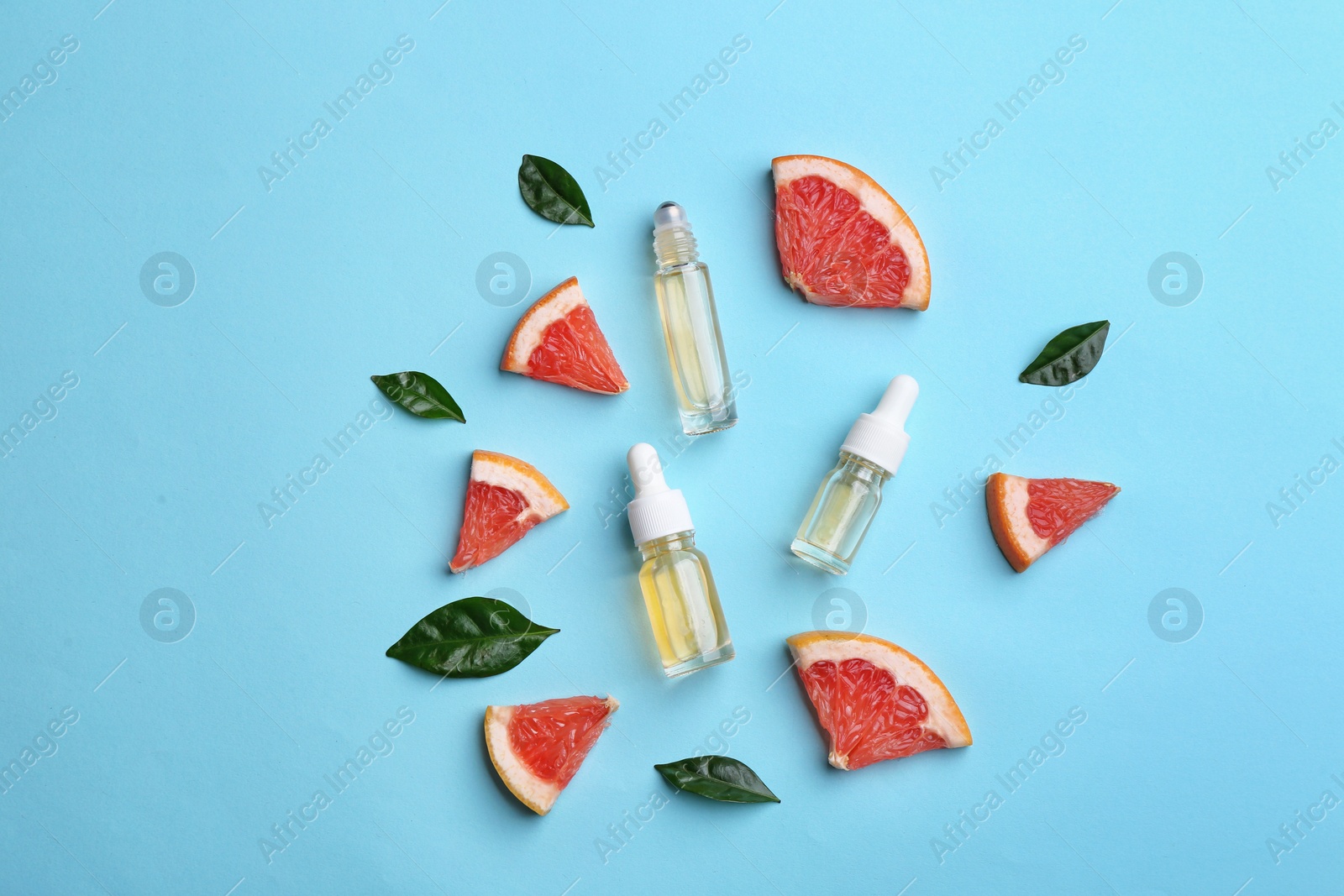 Photo of Flat lay composition with grapefruit slices and bottles of essential oil on color background