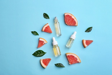 Flat lay composition with grapefruit slices and bottles of essential oil on color background