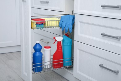 Photo of Open drawer with different cleaning supplies in kitchen