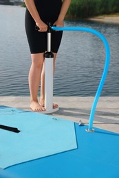 Woman pumping up SUP board on pier, closeup