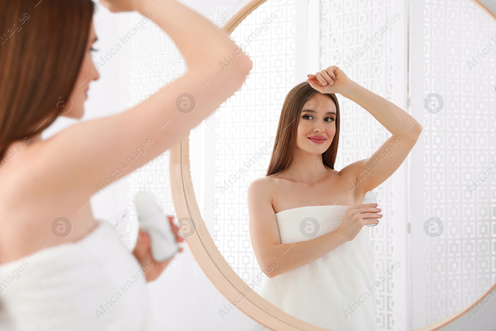 Photo of Beautiful young woman applying deodorant after shower in bathroom