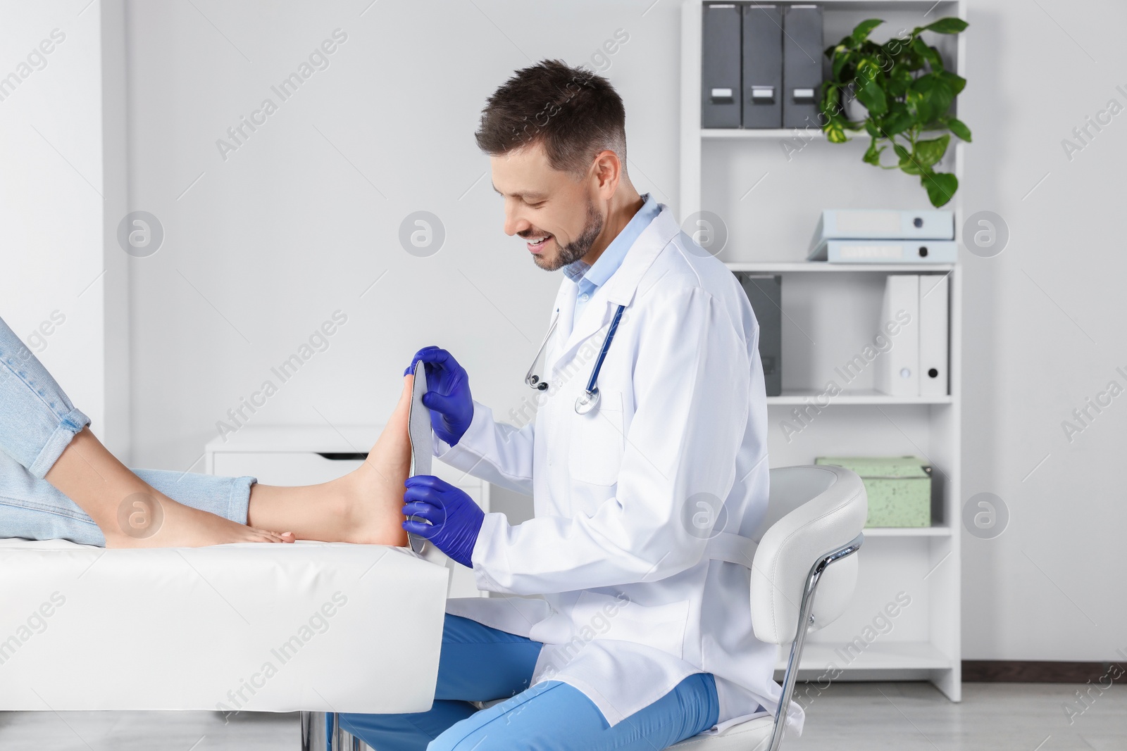 Photo of Male orthopedist fitting insole to patient's foot in hospital