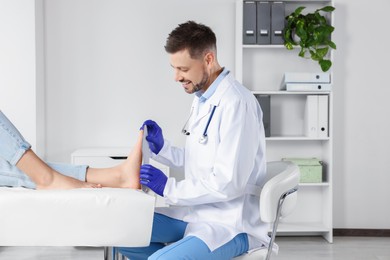 Photo of Male orthopedist fitting insole to patient's foot in hospital