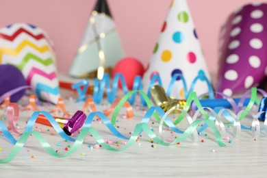 Photo of Colorful serpentine streamers and other party accessories on white wooden table, closeup