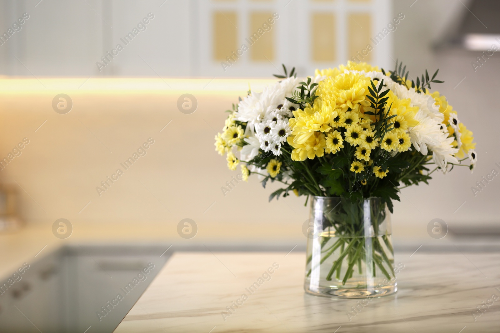 Photo of Vase with beautiful chrysanthemum flowers on table in kitchen, space for text. Interior design