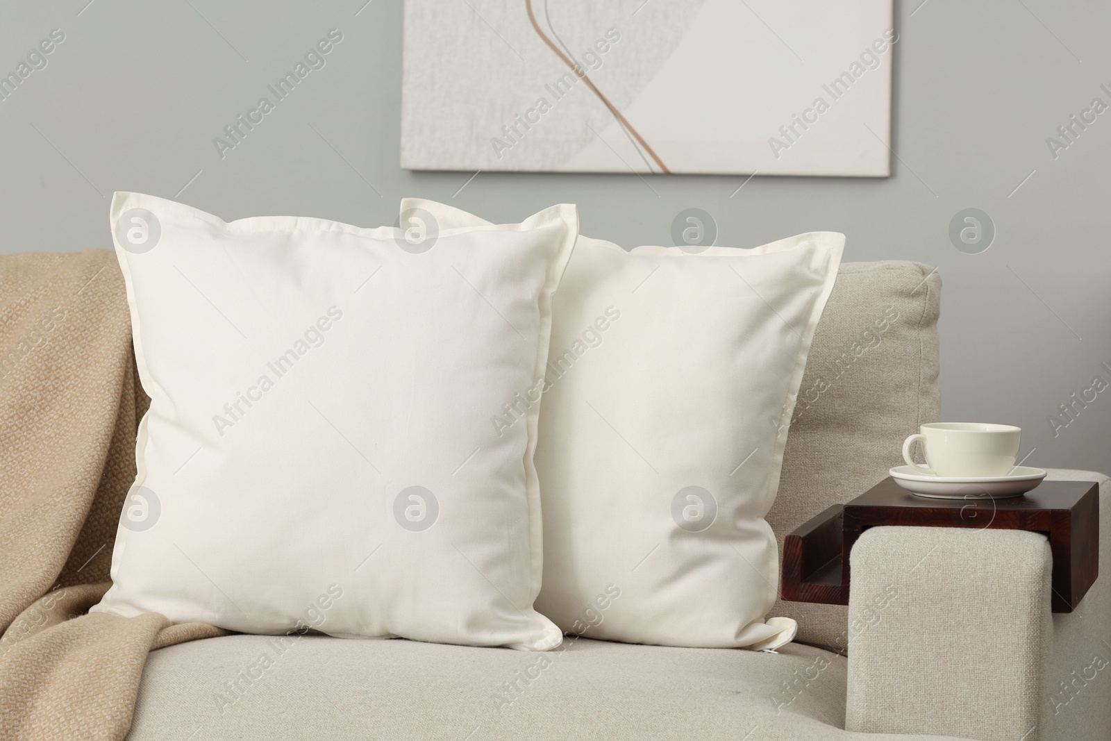 Photo of Soft white pillows and blanket on sofa indoors