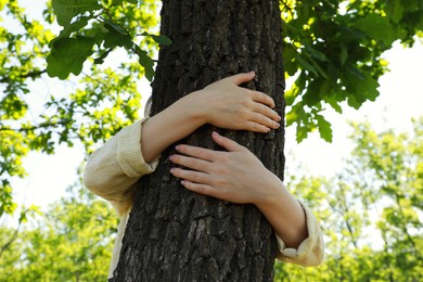 Photo of Woman hugging tree trunk in forest on sunny day