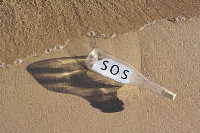 Photo of Glass bottle with SOS message on sand near sea