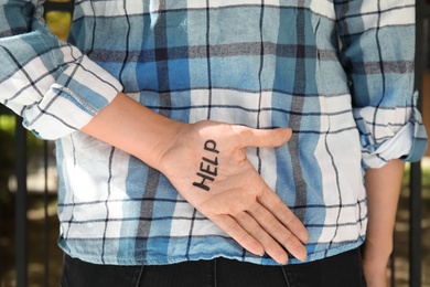 Woman holding hand with word "HELP" behind her back, closeup