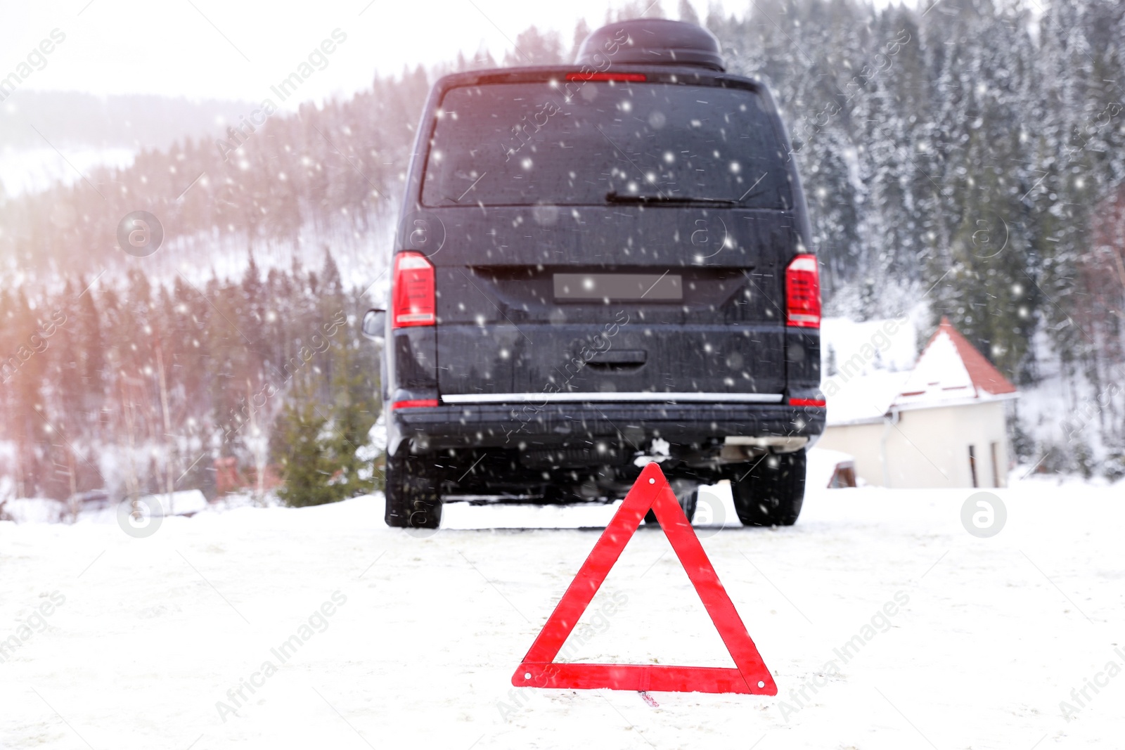 Photo of Emergency stop sign and broken car on snowy road in winter