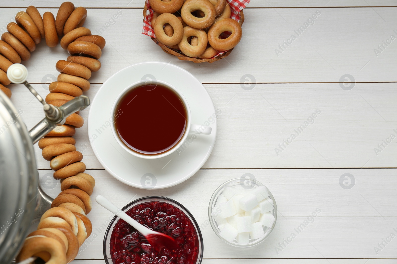 Photo of Flat lay composition with delicious ring shaped Sushki (dry bagels) and cup of tea on white wooden table, space for text