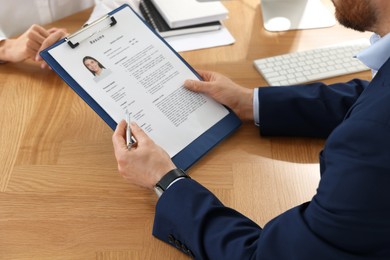 Photo of Human resources manager reading applicant's resume in office, closeup